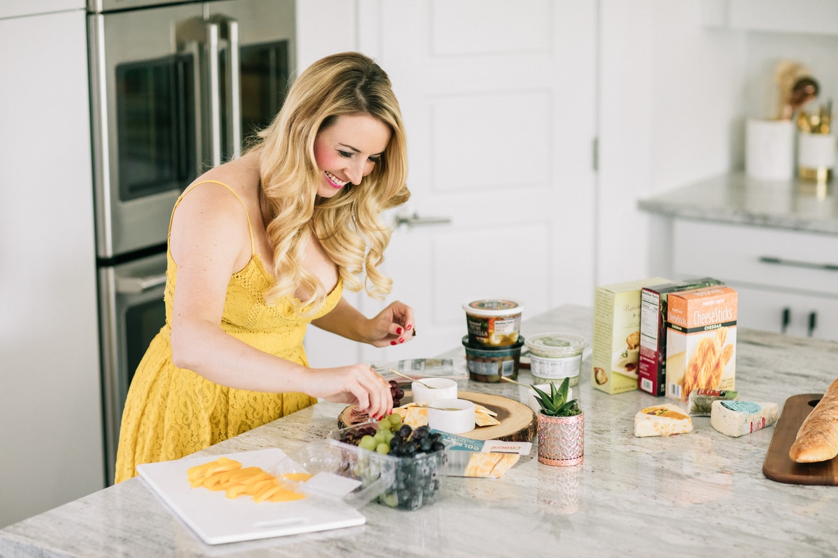 Whitney Bond making a cheese plate with grapes, olives and crackers in kitchen