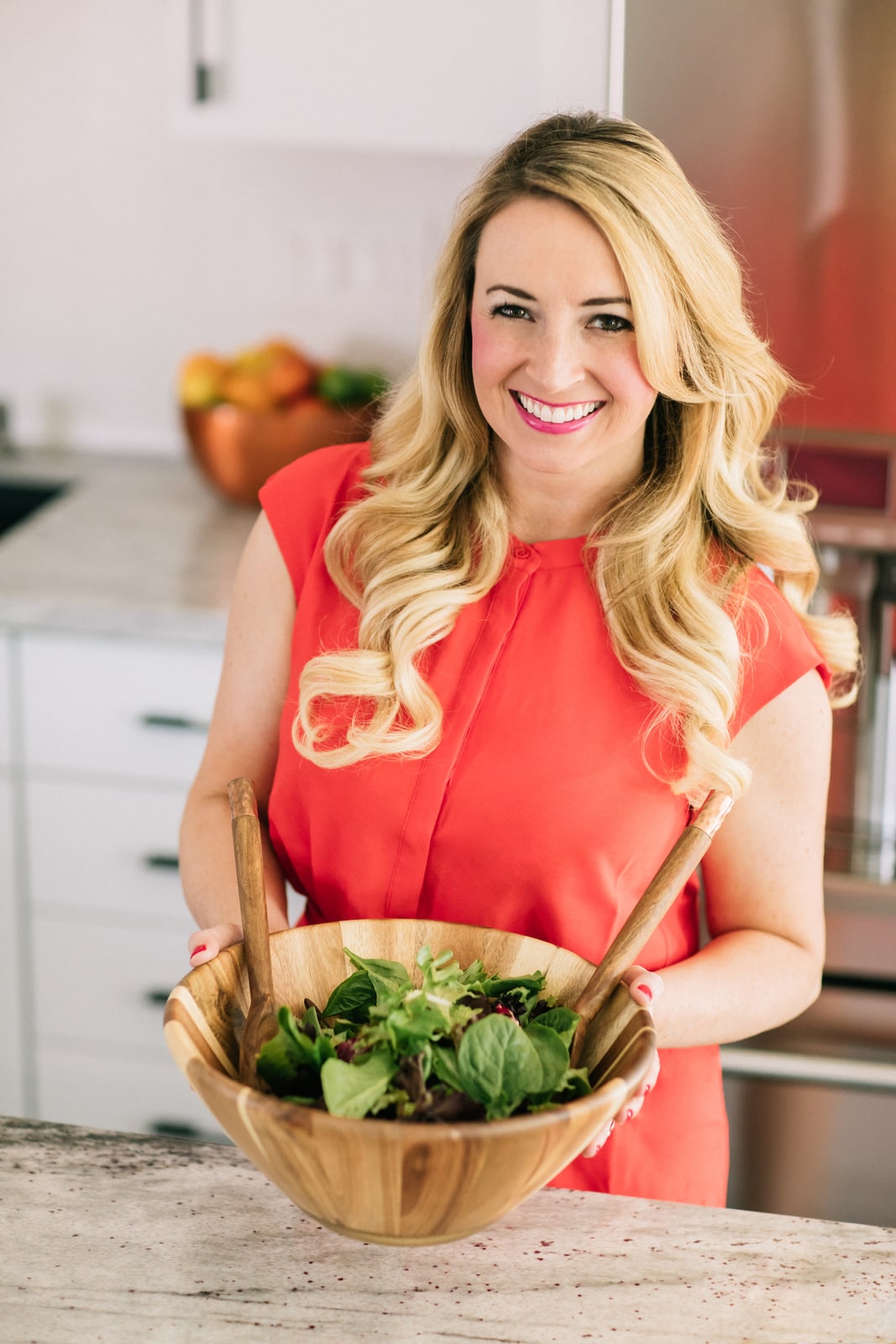 whitney bond in orange dress holding salad bowl in kitchen