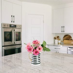 Pink flowers in black and white striped vase on kitchen island