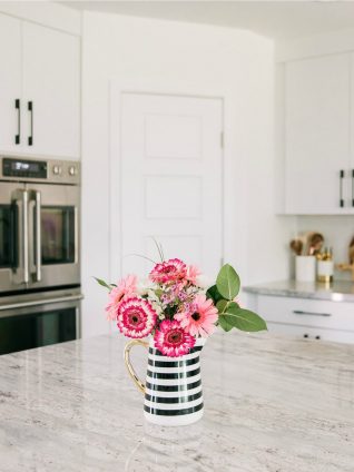 Pink flowers in black and white striped vase on kitchen island