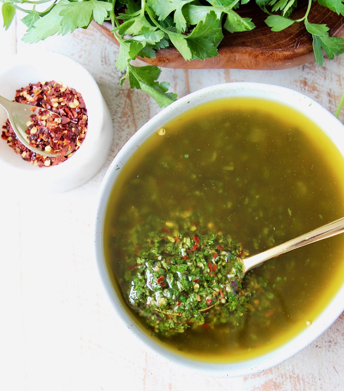 chimichurri sauce in a bowl with a gold spoon