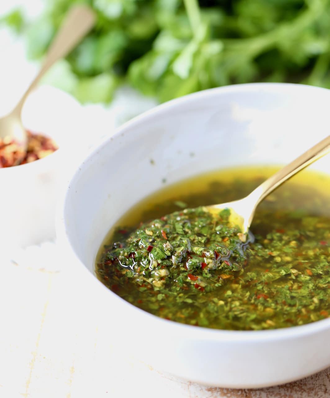 Argentinian Chimichurri Sauce with Parsley, Garlic and Olive Oil in a bowl with a gold spoon