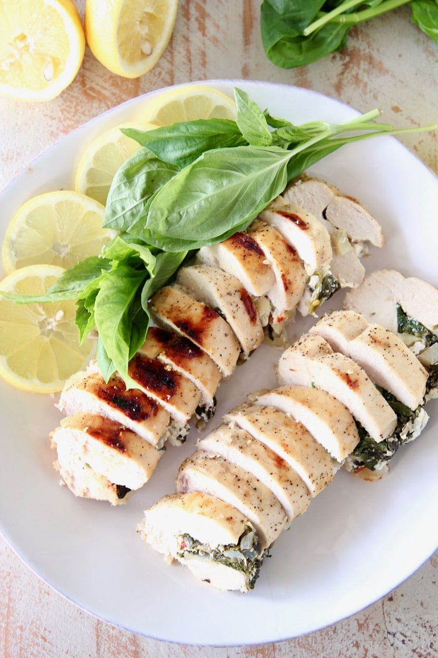 Sliced Spinach Artichoke Stuffed Chicken Breasts with Lemon Slices and Fresh Basil