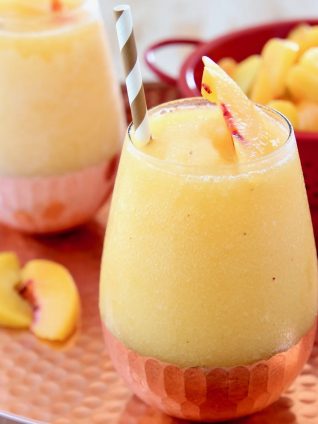 Frozen Peach Sangria in Glasses on Copper Tray with Fresh Peaches in Red Colander