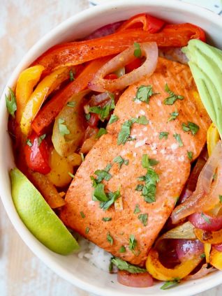 Baked Salmon with Fajita Seasoned Bell Peppers and Onions in Bowl with Sliced Avocado and Lime Wedge