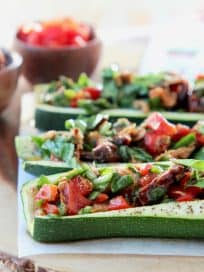 Mediterranean Tuna Salad with Roasted Red Peppers and Sun Dried Tomatoes Stuffed in Roasted Zucchini Boats on Wood Cutting Board
