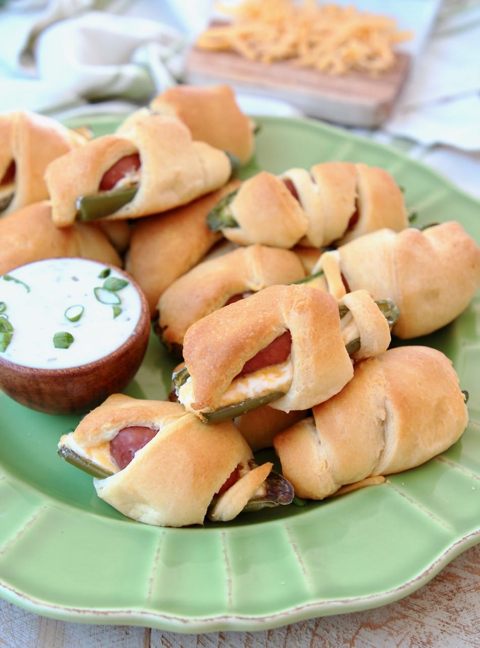 Jalapeno Poppers with a Little Smokie Sausage Wrapped in Crescent Rolls on a Green Plate with Cheddar Cheese and Ranch Dressing