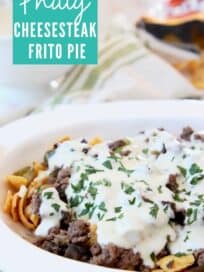 philly cheesesteak frito pie in casserole dish topped with creamy provolone sauce
