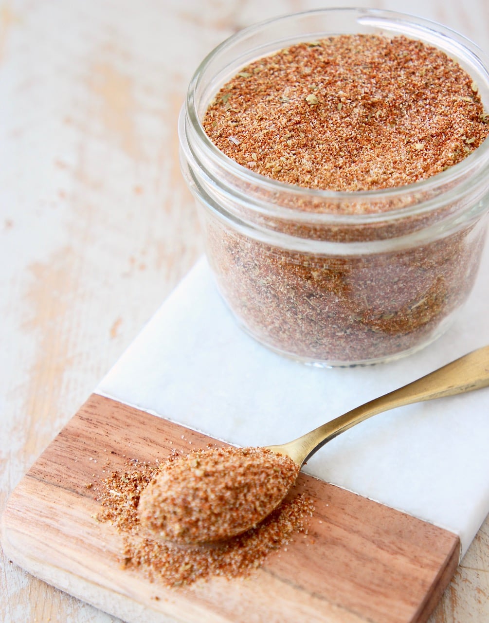 taco seasoning in mason jar on marble cutting board with spoon of taco seasoning