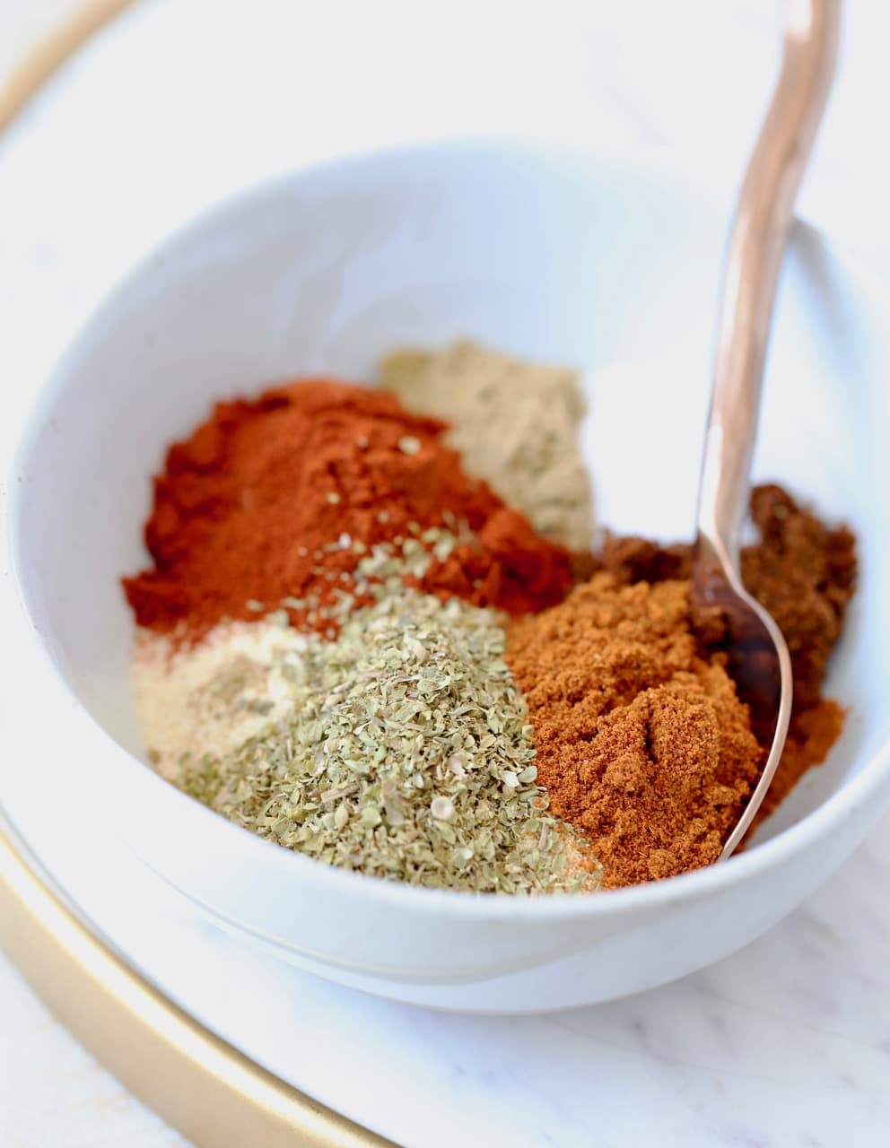 Homemade taco seasoning with 8 different spices in bowl with spoon