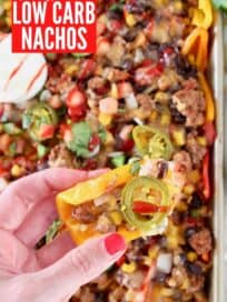 mini pepper nachos on sheet pan with hand holding nacho above the pan