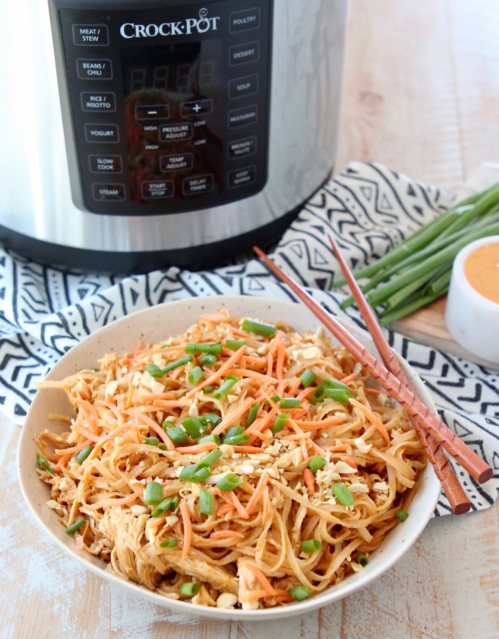 Thai peanut chicken noodles in bowl with chopsticks and Crock Pot Express Crock Multi Cooker