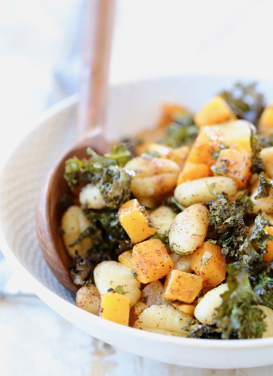 Gnocchi, butternut squash and kale in bowl with wooden spoons