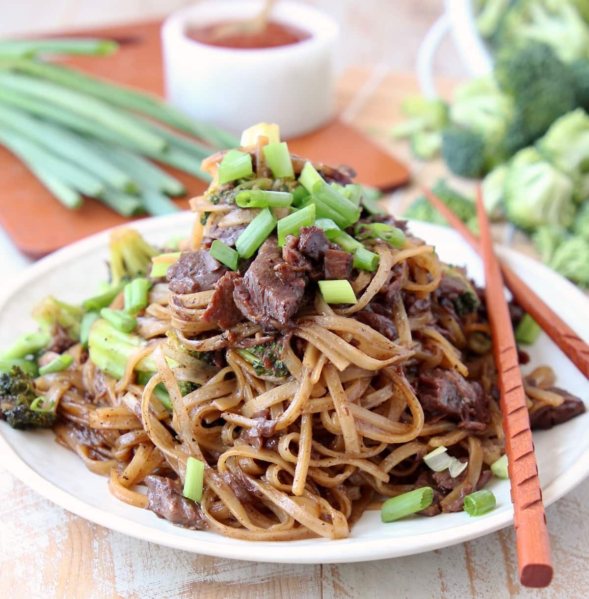 Black Pepper Beef and Brocolli with Rice Noodles and Scallions on plate with wood chopsticks