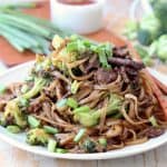 Black Pepper Beef and Broccoli with rice noodles and scallions on plate with chopsticks