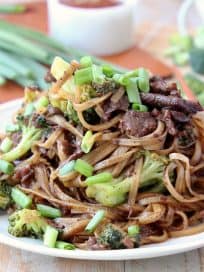 Black Pepper Beef and Broccoli with rice noodles and scallions on plate with chopsticks