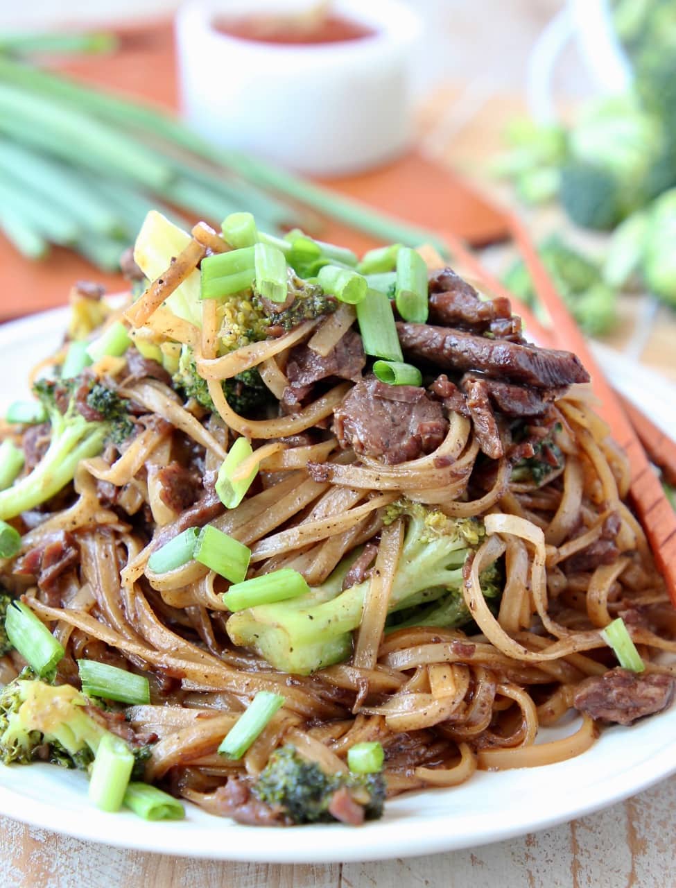 Black Pepper Beef and Broccoli with rice noodles and scallions on plate with chopsticks