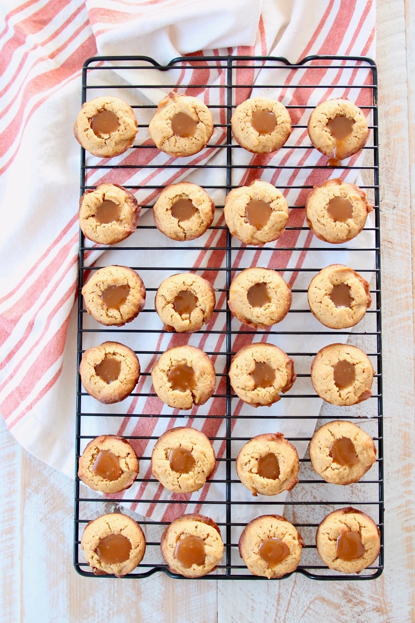 Pumpkin cookies filled with salted caramel on wire baking rack with orange striped towel