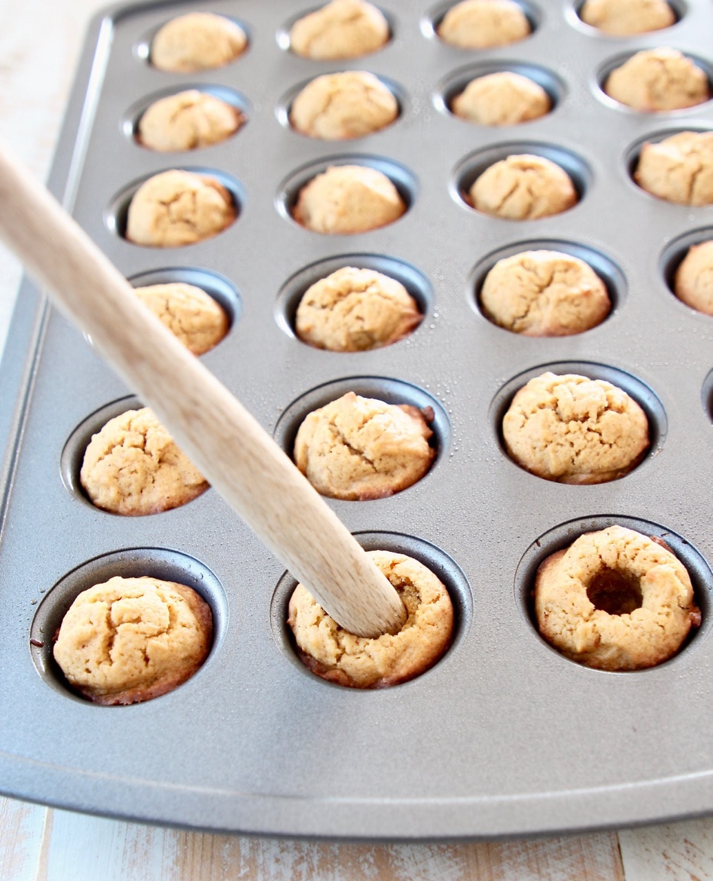 Using the end of a spatula to make pumpkin cookie cups in mini muffin tin