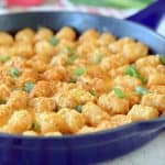Buffalo cheeseburger tater tot casserole in skillet with green onions