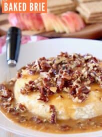 Baked brie on plate covered in salted caramel sauce and pecans
