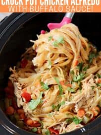 buffalo chicken fettuccine alfredo pasta being scooped out of crock pot with large spoon