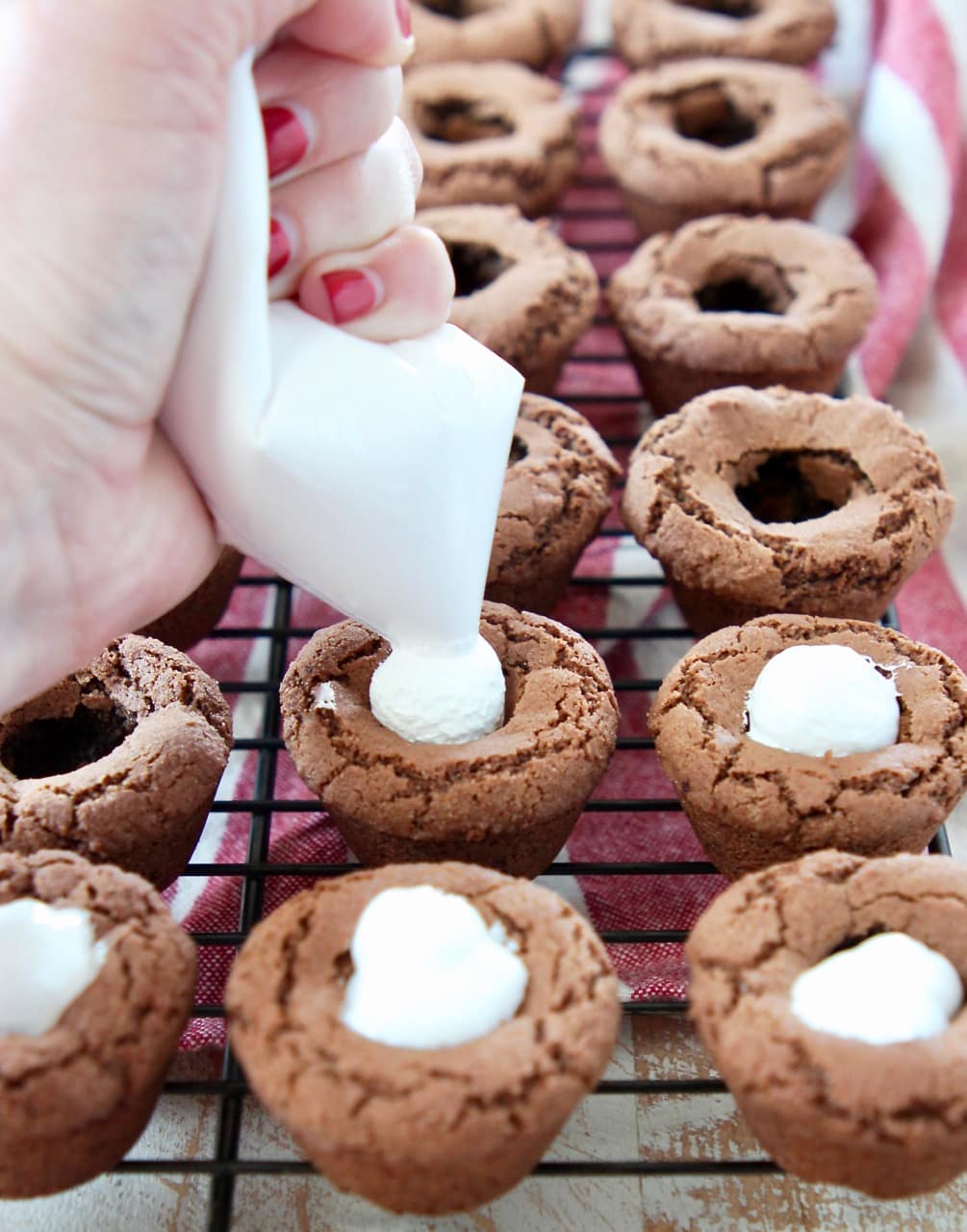 Hot chocolate cookie cups, being filled with marshmallow creme using a piping bag