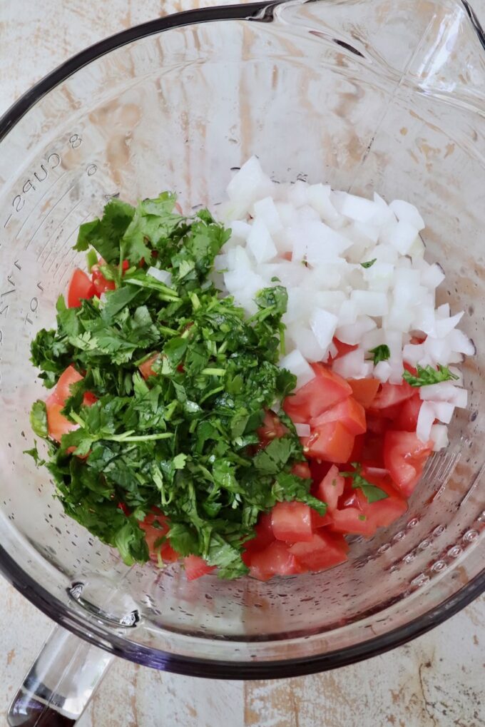 diced tomatoes and onions with fresh cilantro in a glass bowl