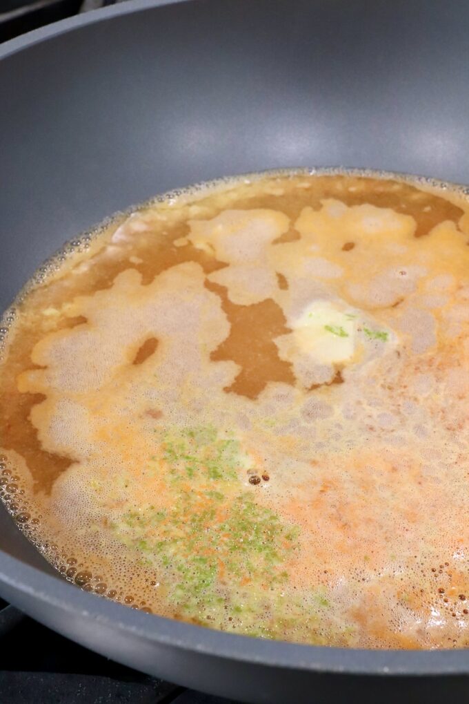 simmering broth in a large pot with lime zest, garlic and ginger