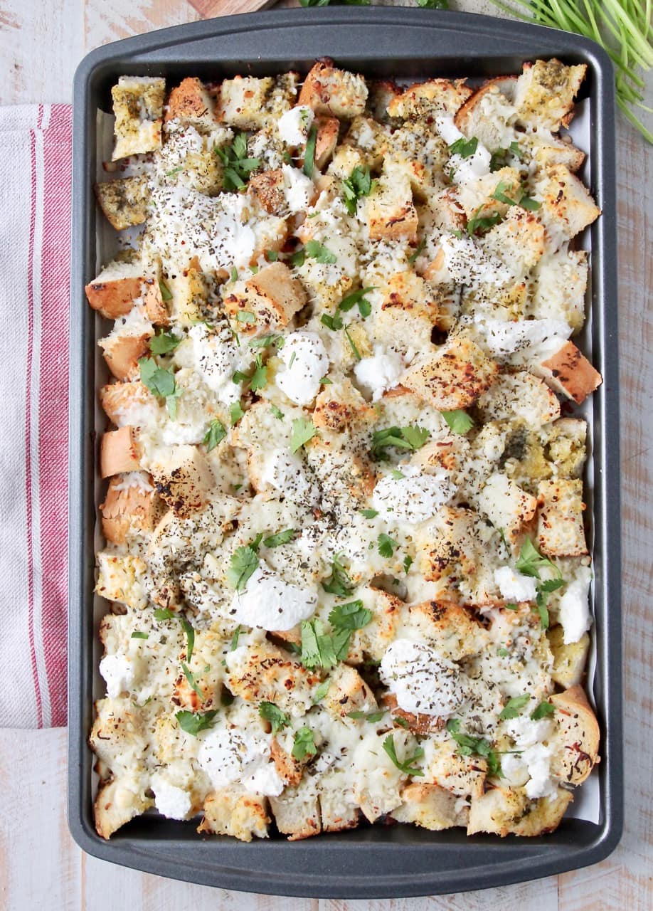 Cheesy garlic bread nachos on a baking sheet, covered with fresh chopped parsley