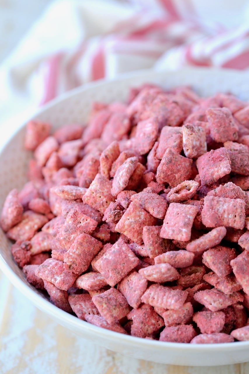 Red velvet puppy chow in white bowl with red and white striped towel