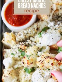 Cheesy garlic bread nachos topped with herbs and cheese, with a bowl of red dipping sauce. Text overlay reads "Easy Appetizer: Cheesy Garlic Bread Nachos Recipe."