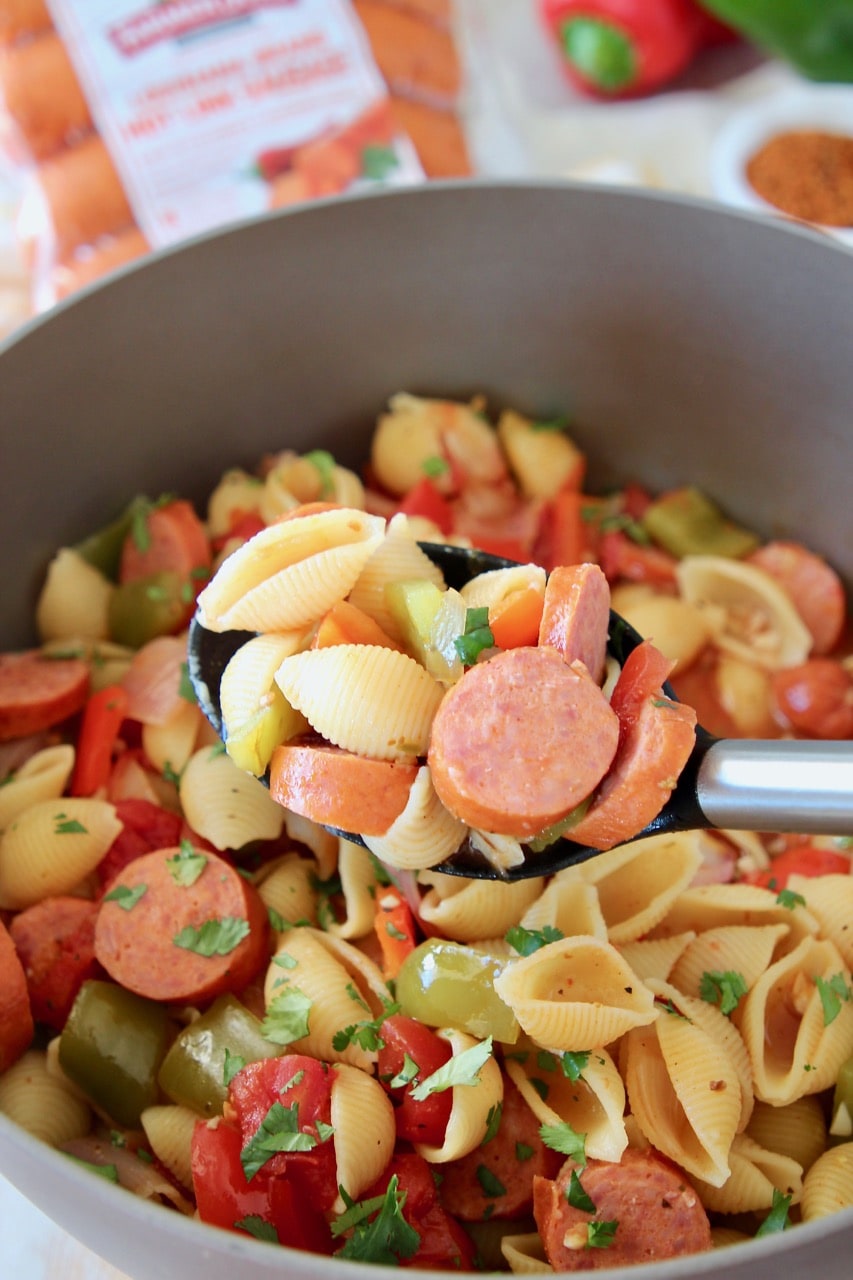 Cajun sausage and pasta in spoon, coming out of pot