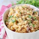 Chicken stroganoff with egg noodles in oval casserole dish with fresh parsley