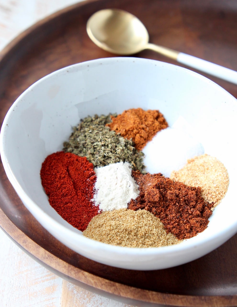 Fajita seasoning spices separated in white bowl on wood tray