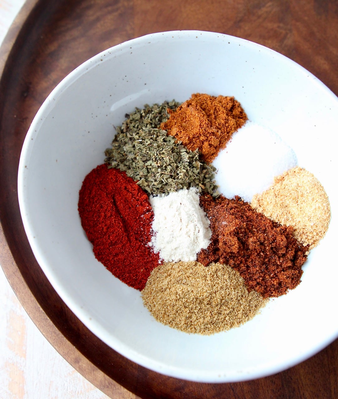 spices separated in white bowl on brown serving tray