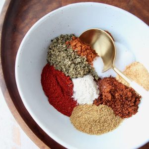 Fajita seasoning spices in white bowl with gold and white spoon in the bowl