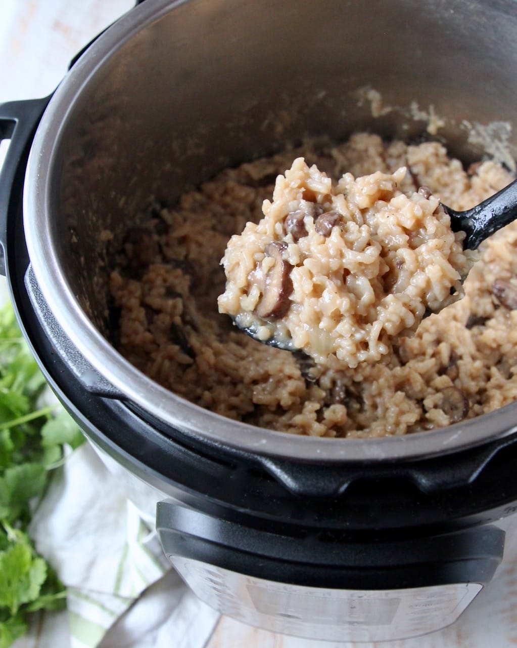 Mushroom risotto in Instant Pot with spoonful of risotto coming out of the Instant Pot 