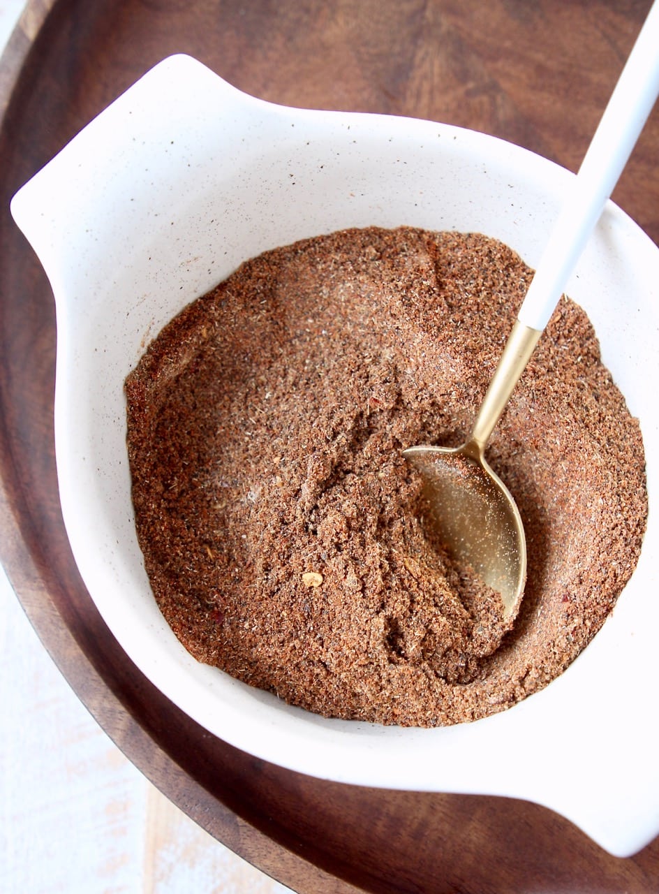 Chili seasoning blend in a white bowl with a gold and white spoon in the bowl