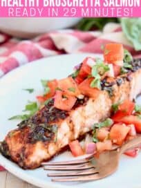 Slice of baked salmon on plate with tomato bruschetta topping