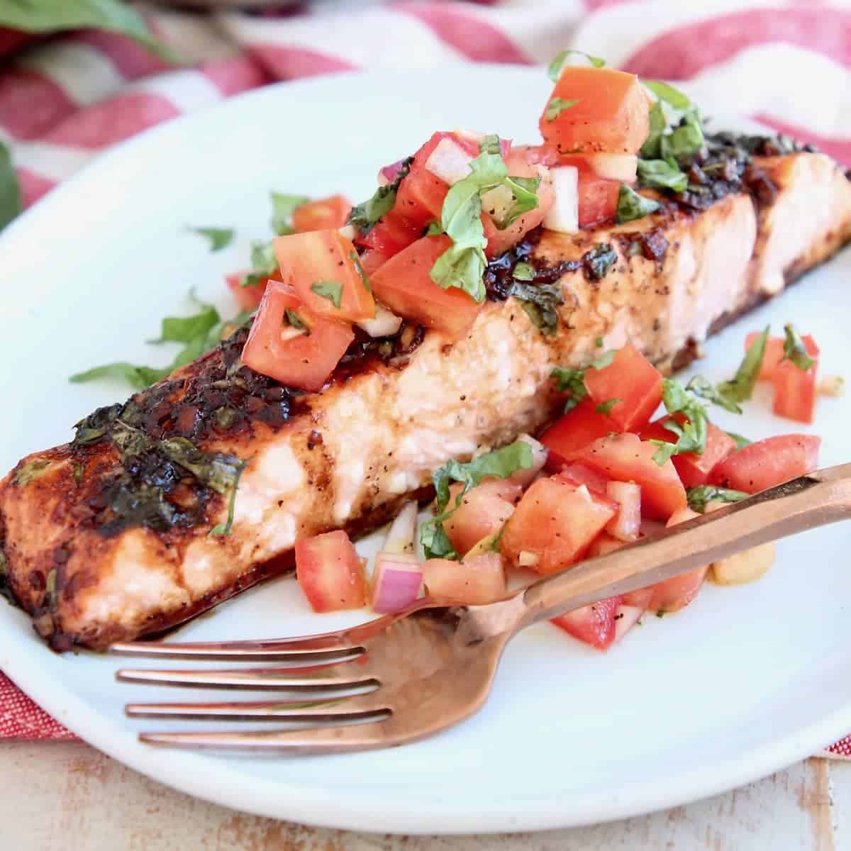 Piece of bruschetta salmon on plate with copper fork