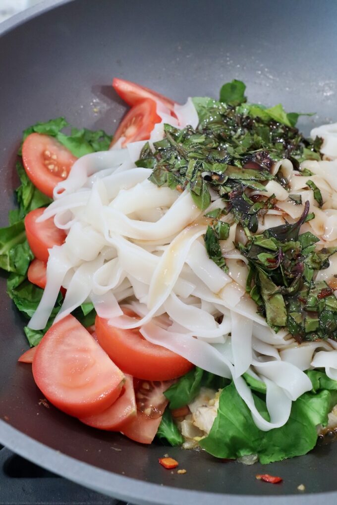 rice noodles in large wok with vegetables and sauce