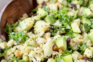 Bowl of diced cauliflower salad with diced avocado, raisins and kale
