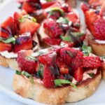 diced strawberries with fresh basil on a toasted piece of bread on a plate