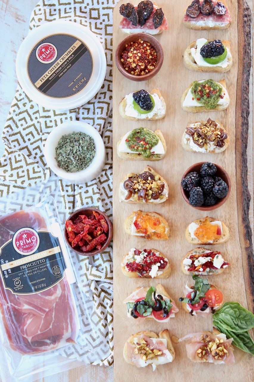 Overhead shot of crostini with different toppings on wood cutting board
