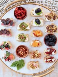 Crostini with various toppings on marble and gold cutting board