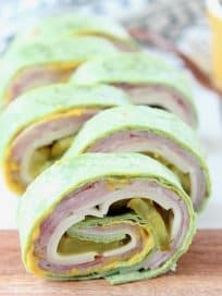 Pinwheel sandwiches with spinach tortillas, ham, cheese, pickles and mustard inside