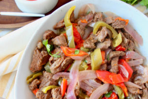 Steak fajitas in bowl with bell peppers and onions