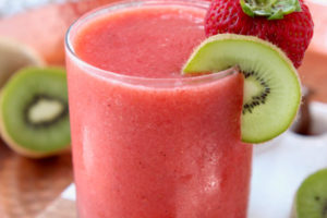 Strawberry slushes in glasses with strawberries and kiwi slices on the side