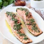 Two pieces of salmon on plate topped with chimichurri sauce